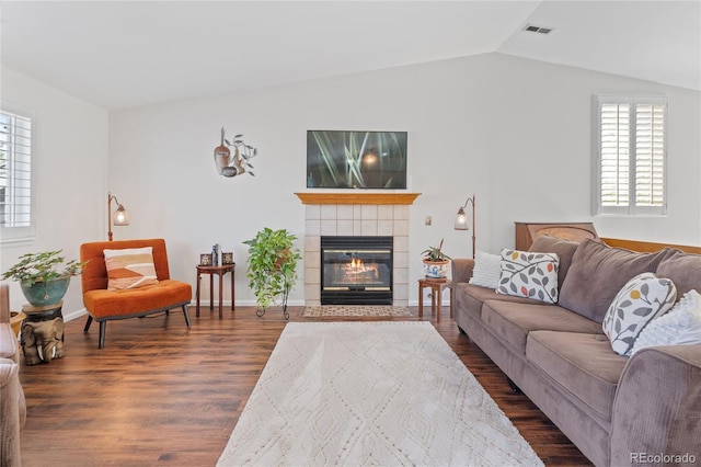 living area featuring vaulted ceiling, dark wood-style flooring, and a fireplace