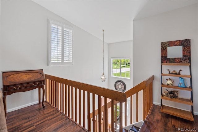 hallway with an upstairs landing, wood finished floors, baseboards, and lofted ceiling