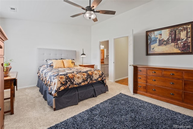 bedroom featuring light carpet, baseboards, a ceiling fan, and ensuite bathroom