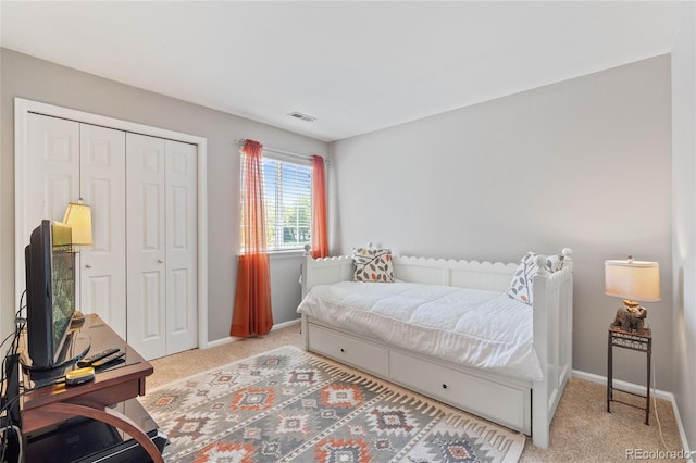 bedroom with light colored carpet, baseboards, and a closet