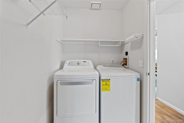 laundry room featuring washer and dryer, wood finished floors, and baseboards