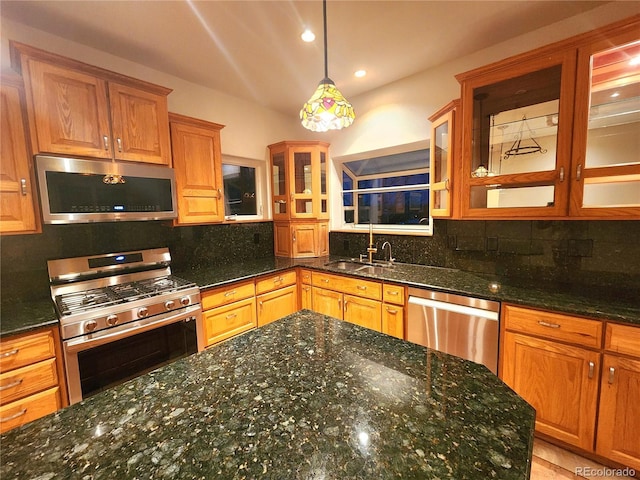 kitchen with appliances with stainless steel finishes, pendant lighting, sink, backsplash, and dark stone counters