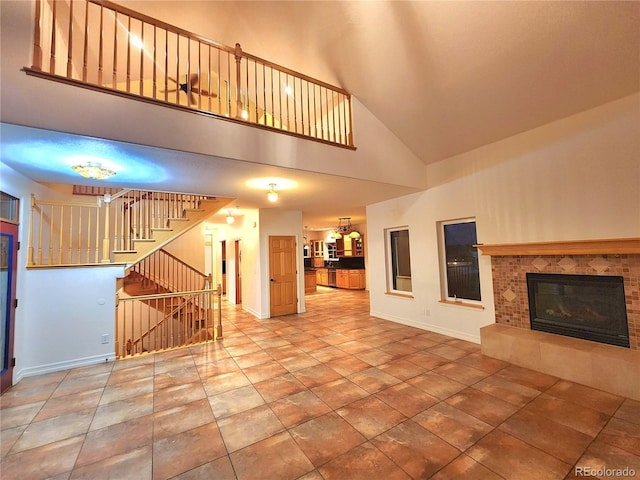 unfurnished living room featuring tile patterned flooring, a tile fireplace, and a high ceiling