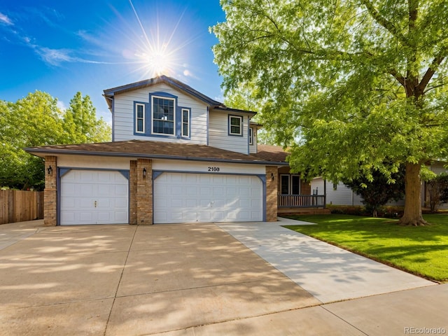 traditional-style house with a garage, brick siding, fence, driveway, and a front lawn