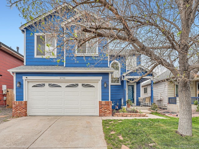 view of front of property featuring an attached garage, driveway, brick siding, and a front yard