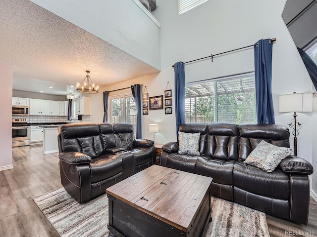 living area with light wood finished floors, a chandelier, and a textured ceiling