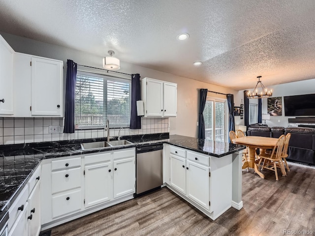 kitchen featuring stainless steel dishwasher, a sink, a textured ceiling, a peninsula, and white cabinetry