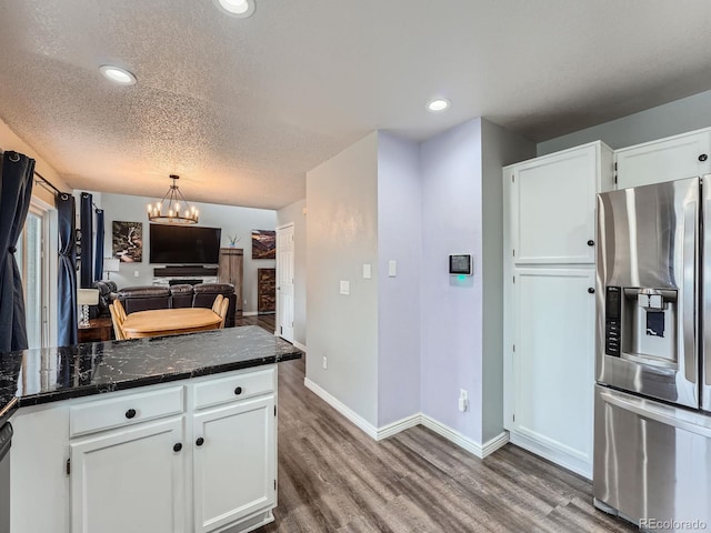 kitchen with stainless steel refrigerator with ice dispenser, wood finished floors, a chandelier, white cabinets, and recessed lighting