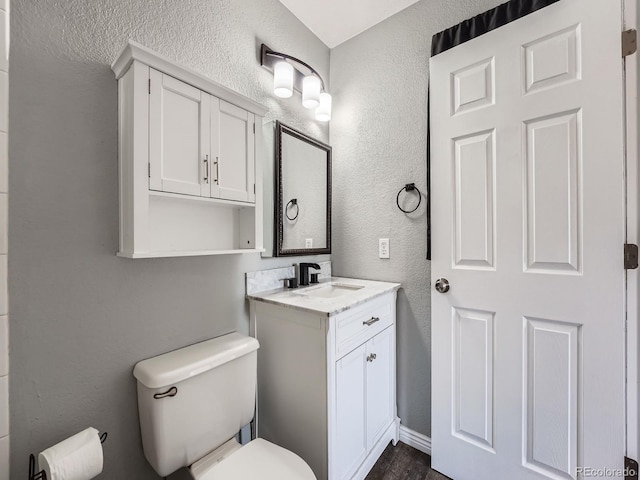 bathroom featuring a textured wall, toilet, vanity, and wood finished floors