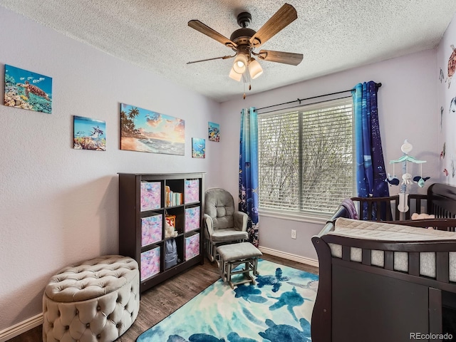 bedroom featuring wood finished floors, a textured ceiling, baseboards, and ceiling fan
