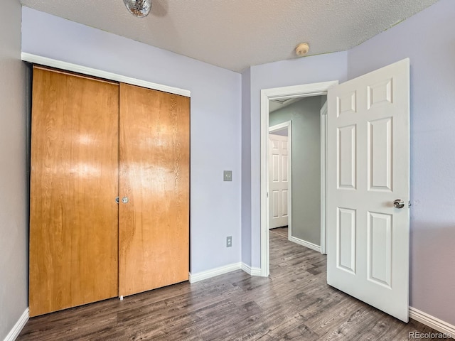 unfurnished bedroom with wood finished floors, baseboards, and a closet