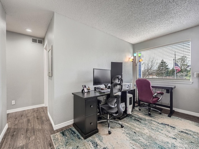 office area featuring a textured ceiling, wood finished floors, baseboards, and a textured wall