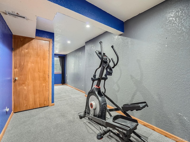 exercise area featuring a textured wall, baseboards, carpet floors, and recessed lighting