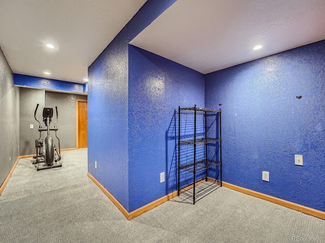 carpeted spare room featuring a textured wall, baseboards, and recessed lighting