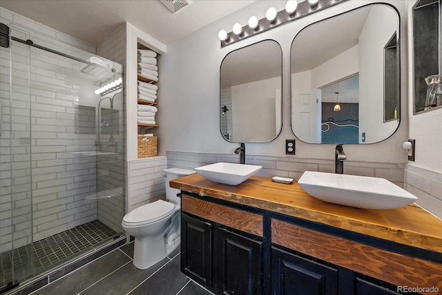 bathroom with tile patterned floors, vanity, a shower with shower door, and toilet