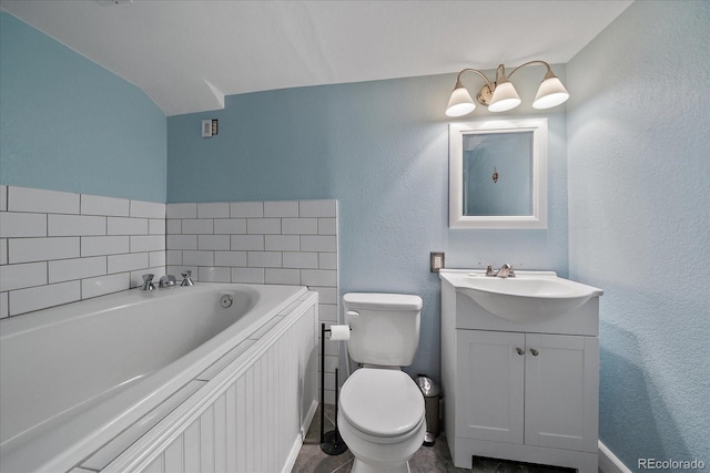 bathroom featuring vanity, a tub to relax in, and toilet