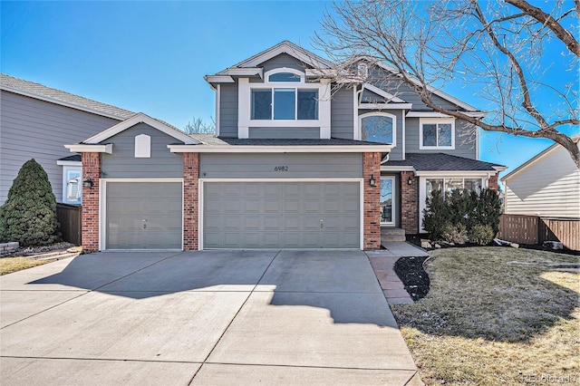 view of front of house with brick siding, driveway, and fence