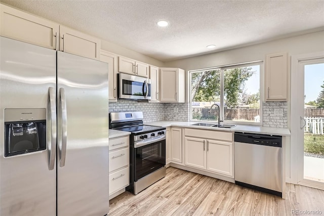 16273 E Brown Pl, Aurora, CO 80013 - kitchen featuring appliances with stainless steel finishes, a textured ceiling, light countertops, tasteful backsplash, and light wood-style flooring