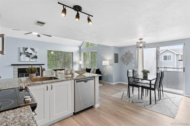 kitchen featuring dishwasher, a sink, baseboards, healthy amount of natural light, and vaulted ceiling