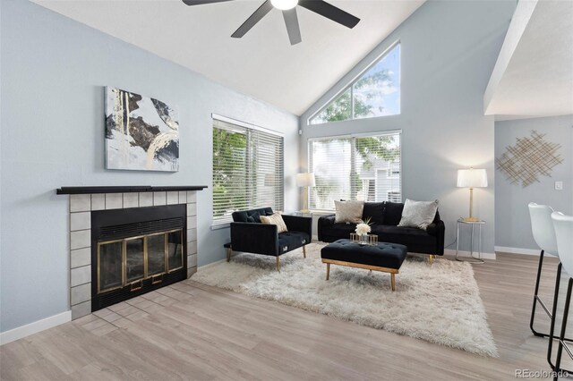 living room with wood finished floors, a ceiling fan, a fireplace, high vaulted ceiling, and baseboards