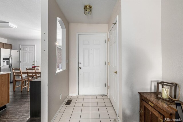 entryway with baseboards, visible vents, and arched walkways