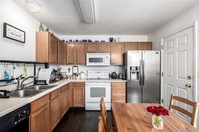 kitchen featuring dark wood-type flooring, a sink, white appliances, and a textured ceiling