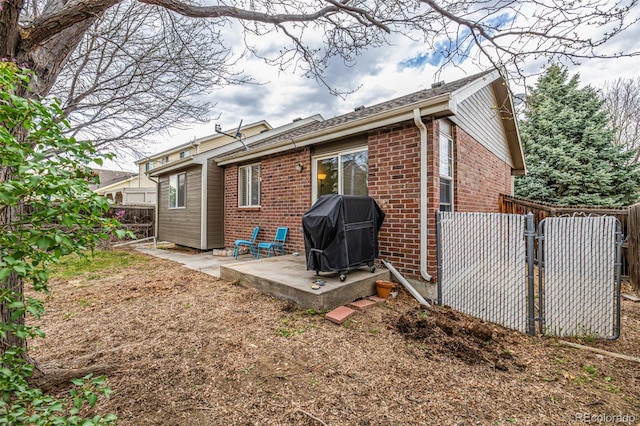 back of house featuring a fenced backyard, brick siding, and a patio area