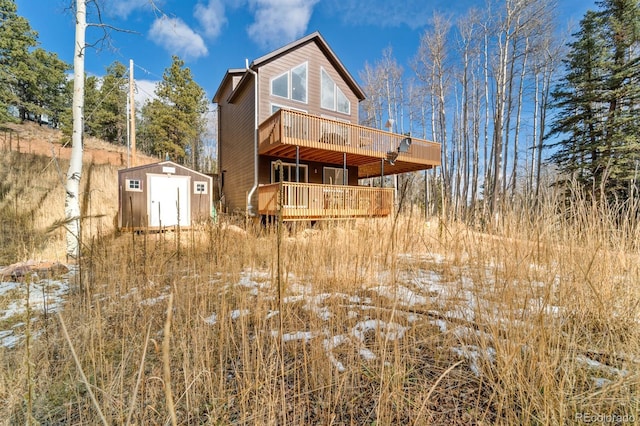 rear view of property with a deck and a shed