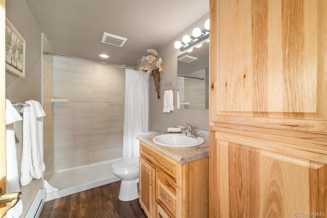 bathroom with hardwood / wood-style flooring, a baseboard heating unit, vanity, toilet, and walk in shower