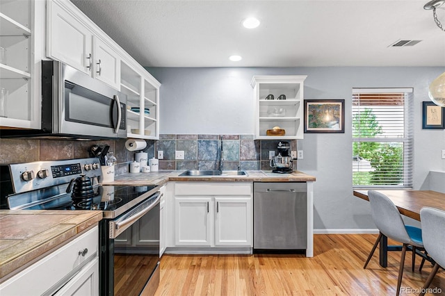 kitchen featuring light wood-type flooring, stainless steel appliances, sink, and white cabinets