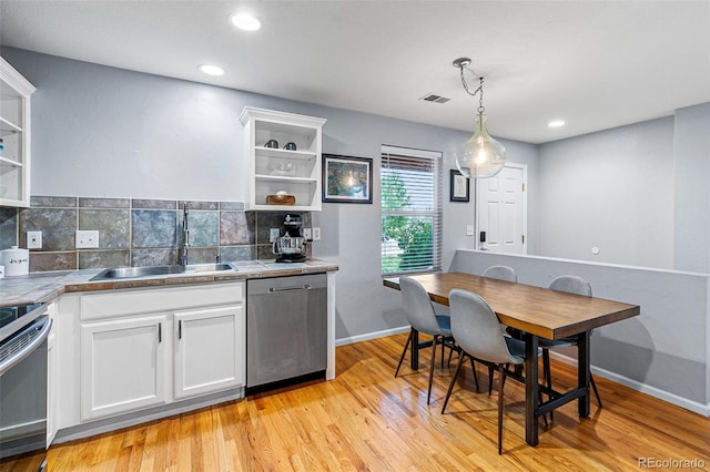 kitchen with sink, white cabinetry, hanging light fixtures, light hardwood / wood-style flooring, and appliances with stainless steel finishes