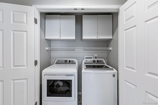 clothes washing area featuring cabinets and washing machine and dryer