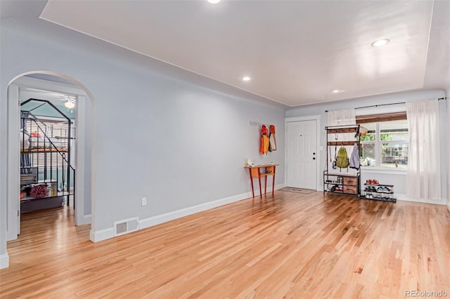 living room featuring arched walkways, light wood finished floors, baseboards, and recessed lighting