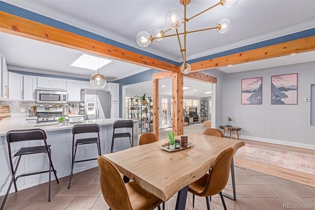 dining room with light tile patterned floors, a chandelier, crown molding, and a skylight