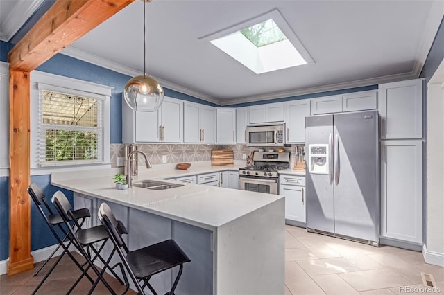 kitchen featuring stainless steel appliances, a sink, a skylight, a peninsula, and light countertops
