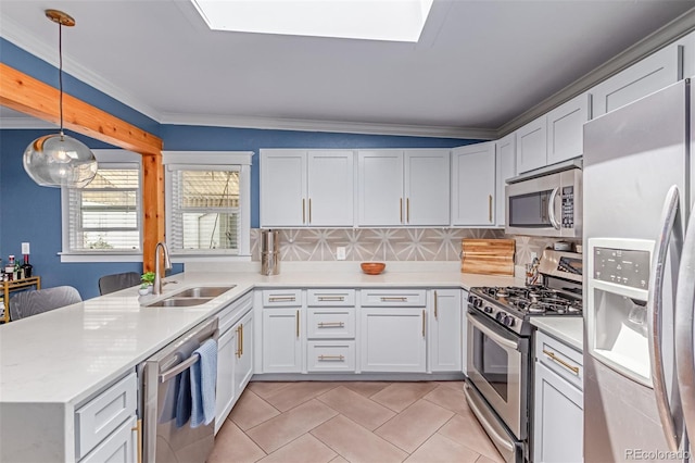 kitchen with appliances with stainless steel finishes, a sink, light countertops, white cabinetry, and hanging light fixtures