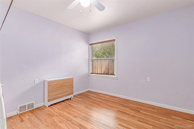 unfurnished room with a ceiling fan, baseboards, and light wood-type flooring