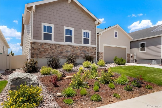 view of front of house featuring an outbuilding, stone siding, fence, a front yard, and a garage