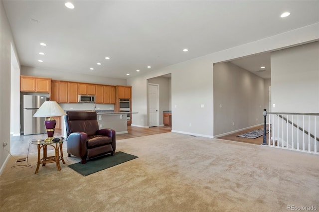 interior space with light colored carpet, recessed lighting, a center island with sink, and stainless steel appliances