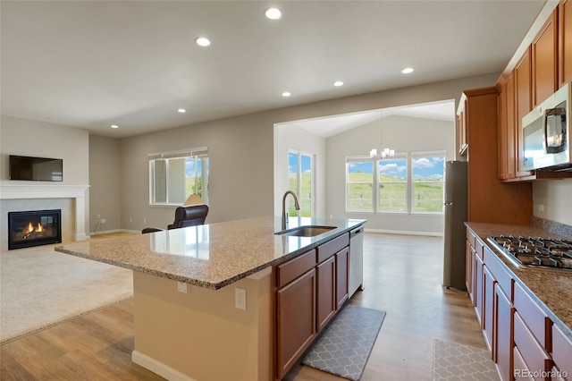 kitchen with light stone counters, recessed lighting, a glass covered fireplace, stainless steel appliances, and a sink