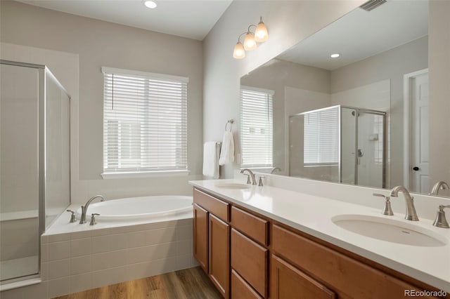 bathroom with a shower stall, wood finished floors, a garden tub, and a sink