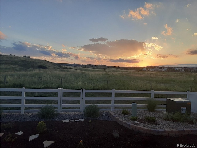 yard at dusk with a rural view and fence