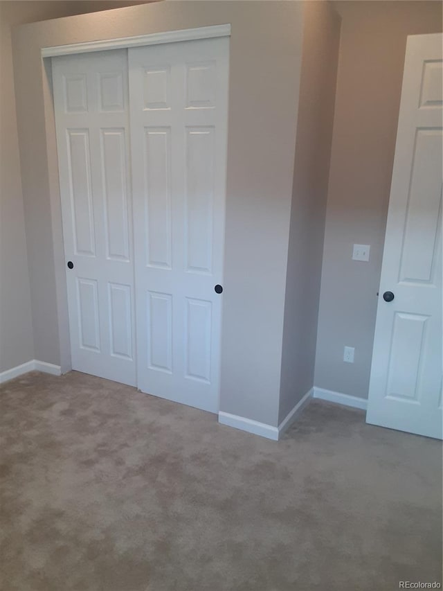 unfurnished bedroom with a closet, baseboards, and carpet