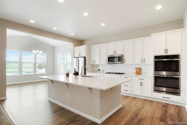 6070 Long Branch Dr, Parker, CO 80134 - kitchen featuring stainless steel appliances, light wood-style flooring, a sink, a kitchen island with sink, and lofted ceiling