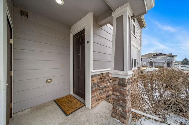 snow covered property entrance with stone siding