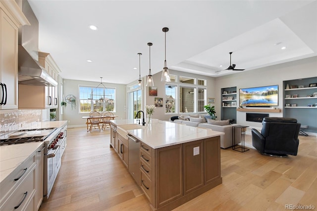 kitchen with wall chimney range hood, appliances with stainless steel finishes, a ceiling fan, recessed lighting, and light wood-type flooring