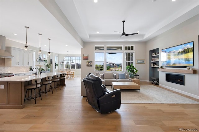 living room with a ceiling fan, recessed lighting, a lit fireplace, and light wood-style flooring