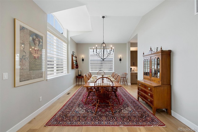 dining space with a chandelier, visible vents, baseboards, lofted ceiling, and light wood-style flooring