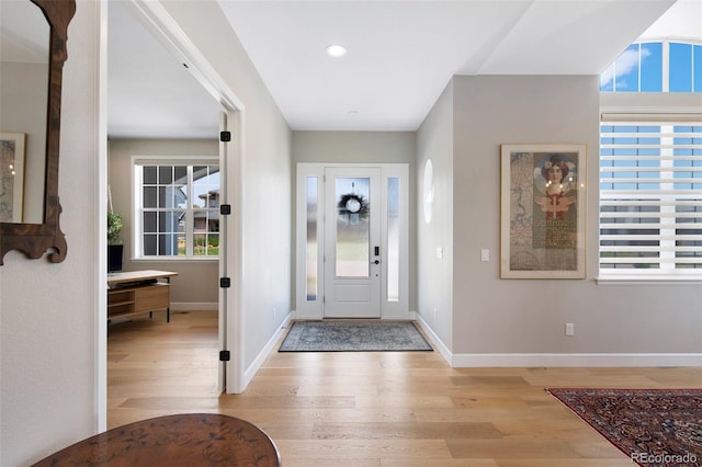 entrance foyer with baseboards, a healthy amount of sunlight, and light wood-style floors