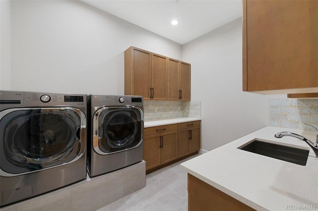 laundry area with a sink, cabinet space, light tile patterned floors, and washing machine and dryer